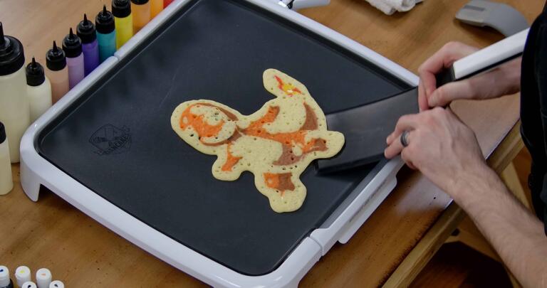 Charmander Pancake Art step 9.3: When the pancake seems cooked through, begin to 'carve' it, by gently loosening it from the griddle surface with the edge of your spatula. Work your way around the outside edge until the pancake releases from the griddle.