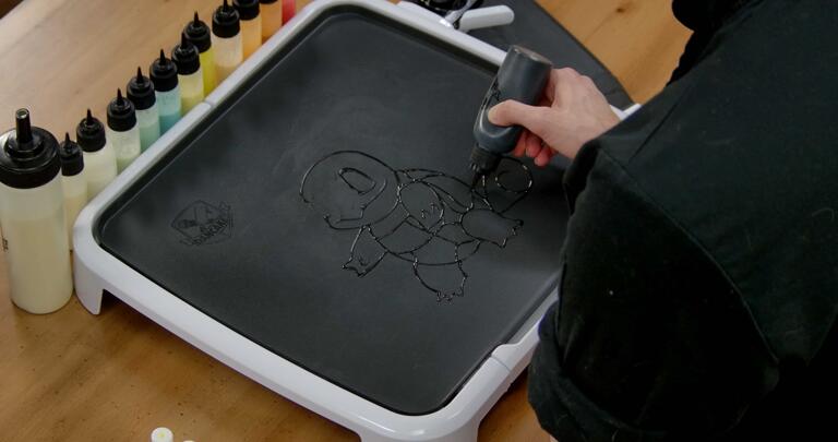 Squirtle Pancake Art step 1.3: Finish up Squirtle's outline with the tail, and then add minor details like a swirl on the tail, and segments on the chest and shell.
