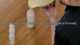 This image shows the batter being poured into the Dancakes Fill Bottle from the mixing bowl, and says "Pour batter into your fill bottle (or grab a funnel)"