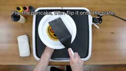 An image of the heart eyes emoji pancake design being flipped onto the plate. The image reads: "Flip the pancake, then flip it onto the plate."